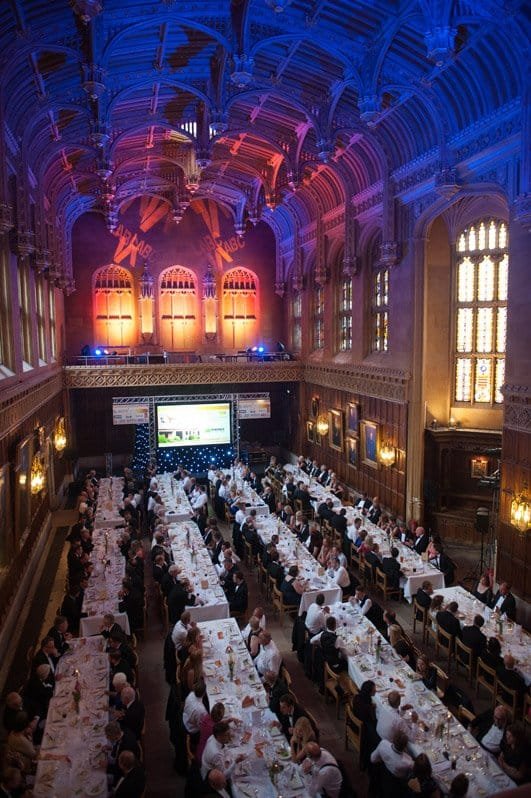 Elegant corporate event in historic venue with professional photographers capturing moments.