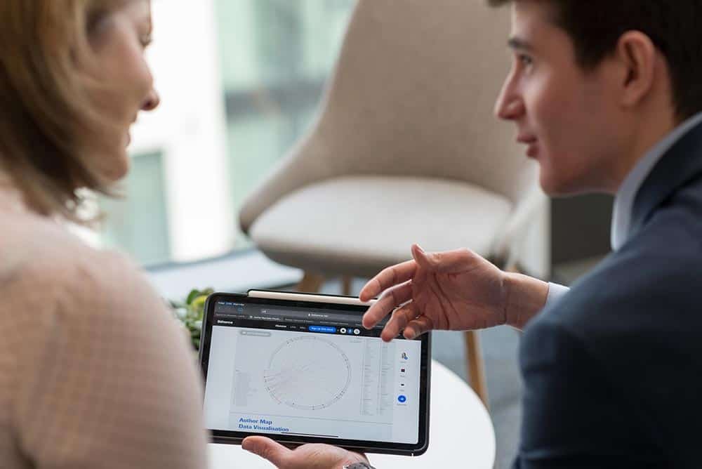 Why Custom Stock Photography Beats Generic Images 10 Professional business discussion with tablet showcasing data analysis at corporate event.