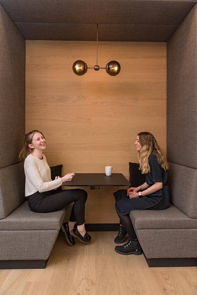 Why Custom Stock Photography Beats Generic Images 6 Friendly business women having a conversation in modern office booth.