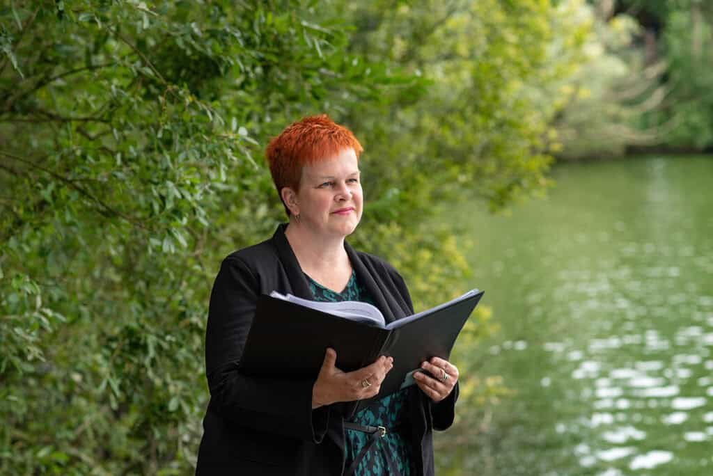 Professional woman reading outdoors near a river, for corporate photography and headshot sessions.