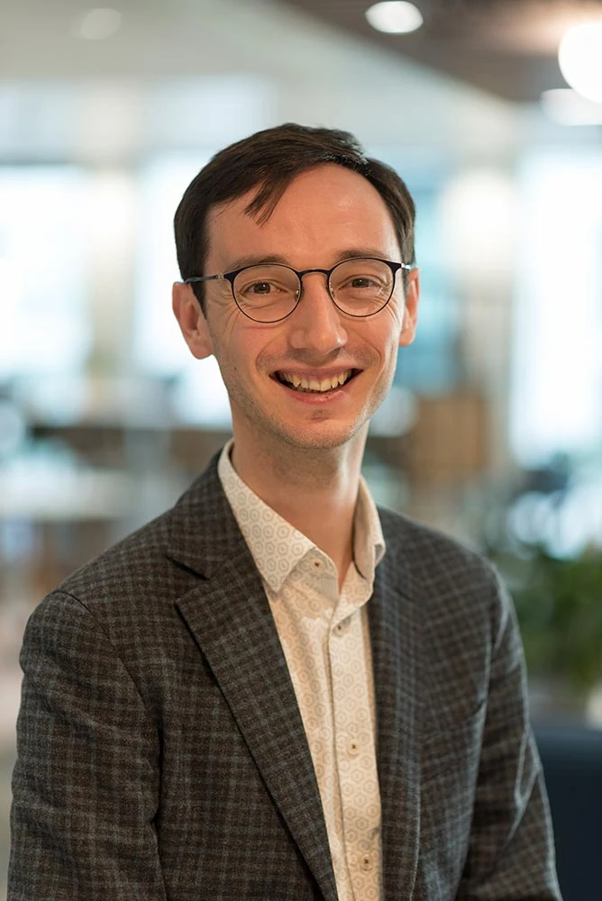 A relaxed professional portrait with a softly blurred office background