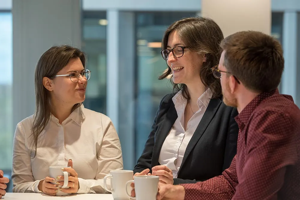 Three colleagues talking across a meeting-room table